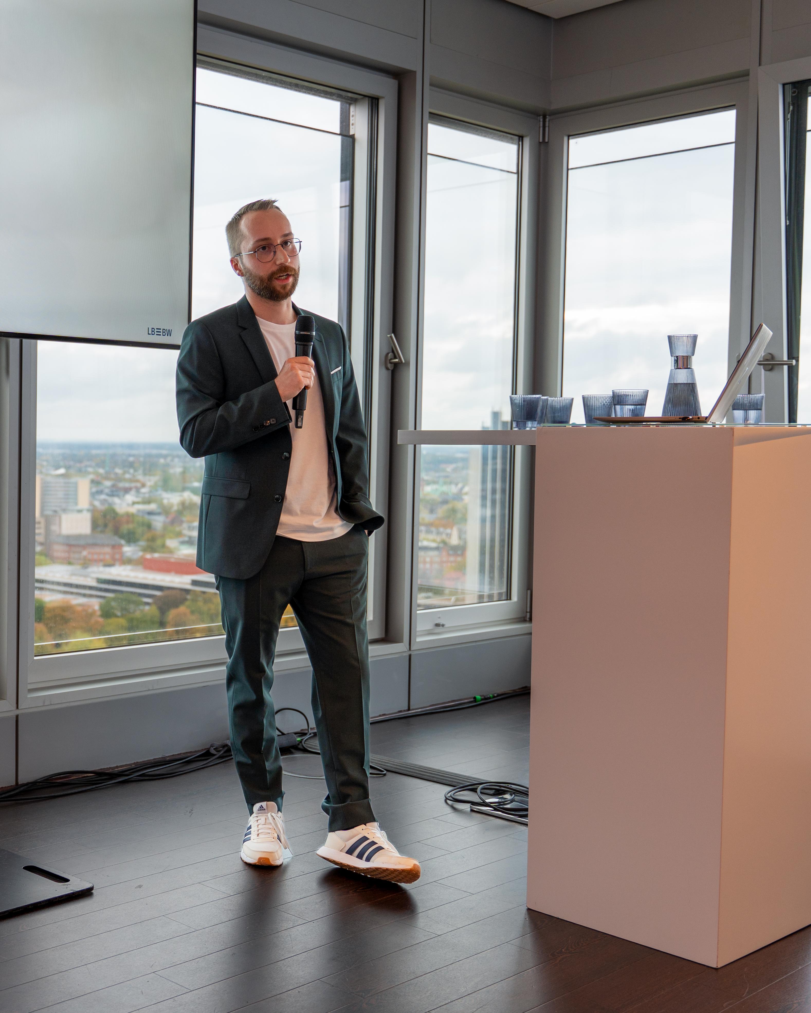 Sebastian Bodza presenting on stage at AI.SUMMIT Hamburg